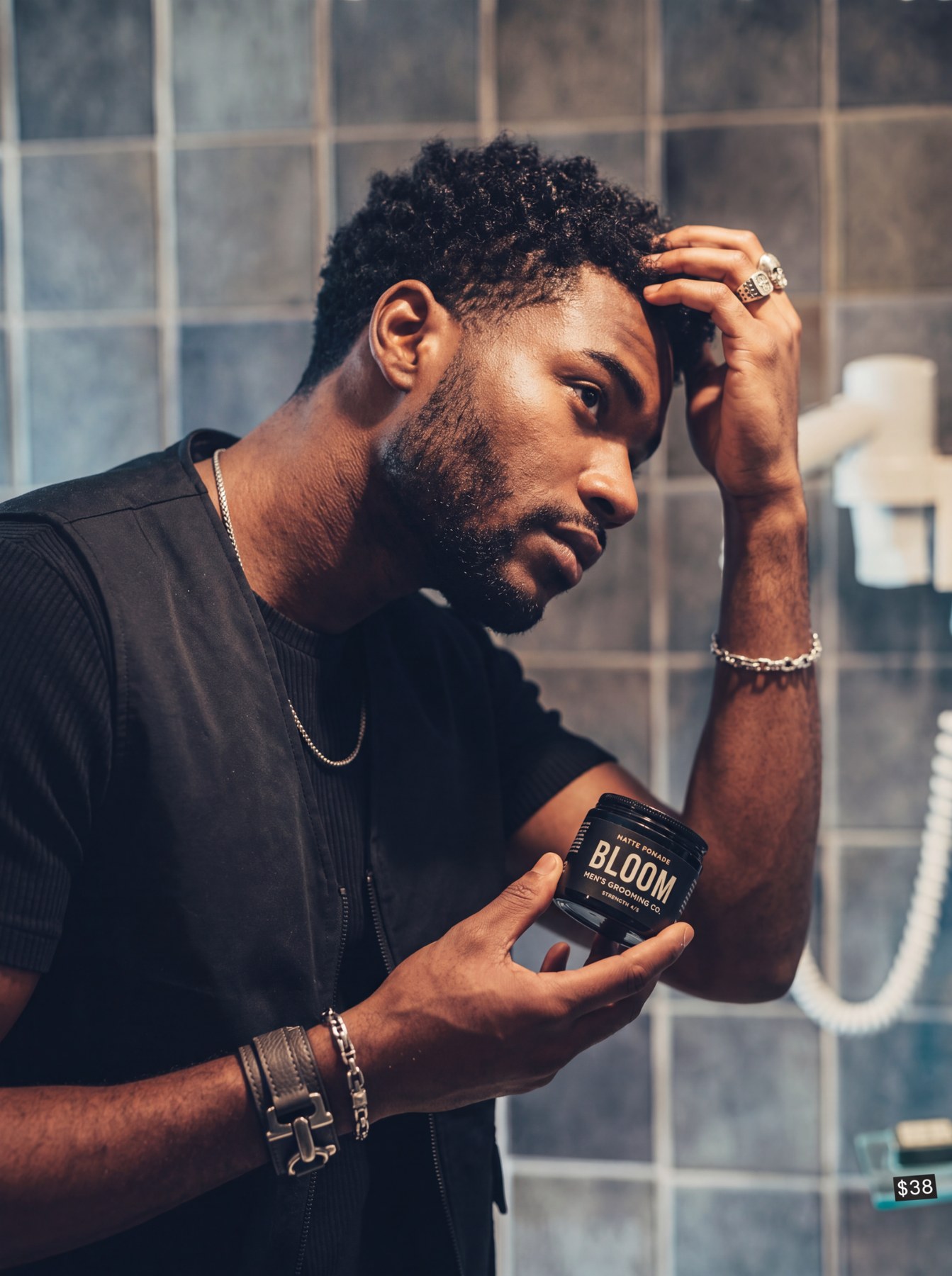 Man in a bathroom applying hair product while holding a Bloom grooming pomade jar.